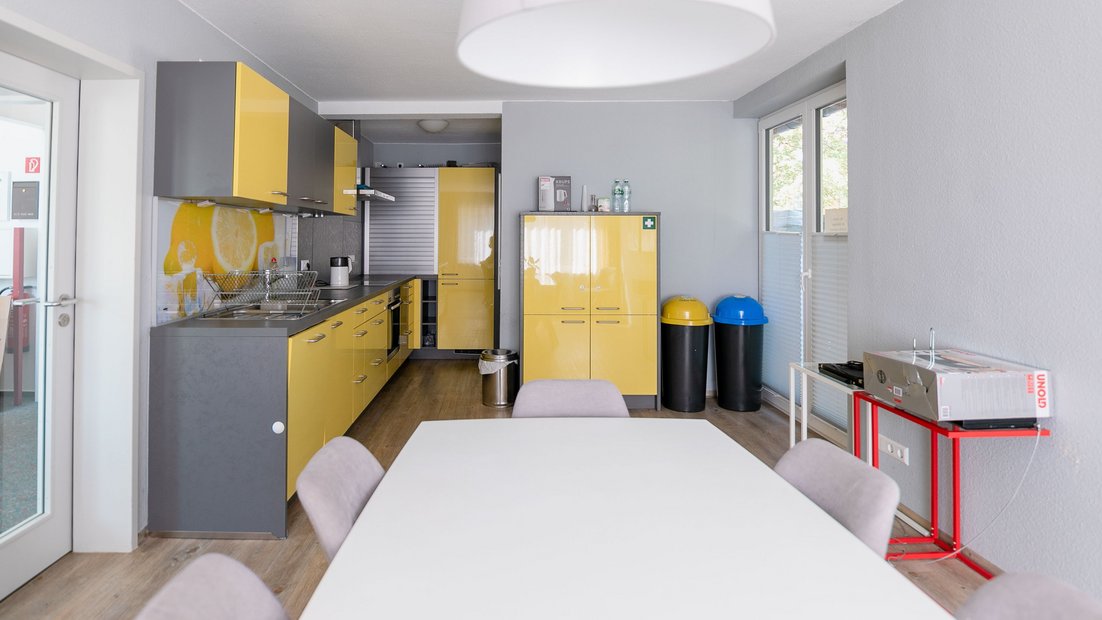 Современная мини-кухня в серо-желтом цвете с обеденным столом на переднем плане