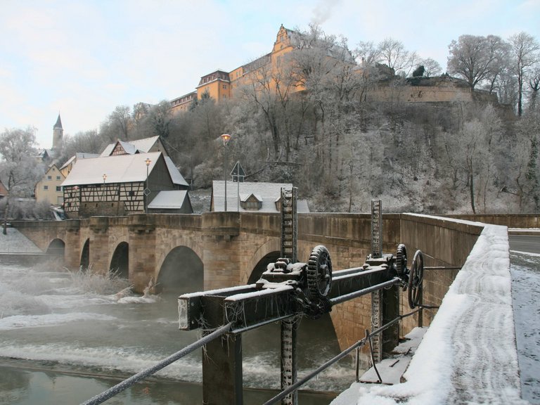 Зимний вид на каменный мост с круглыми арками и плотиной на замке Берг Кирхберг