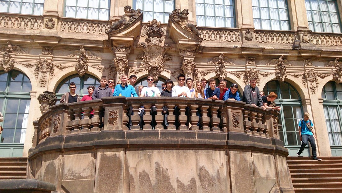 Группа студентов стоит на балконе исторического здания.