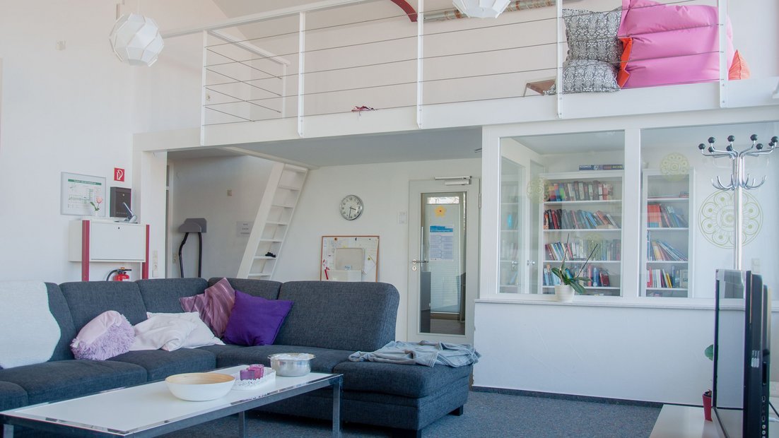 Вид на общую зону внизу с уютным диванным уголком, витриной белой книги и белой галереей